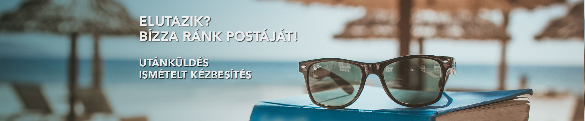 A képen tengerparti háttér előtt egy könyv és egy napszemüveg látható.